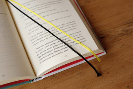 Foto del detalle de dos cintas de registro (amarilla y negra) en un libro abierto encuadernado en tapa dura.