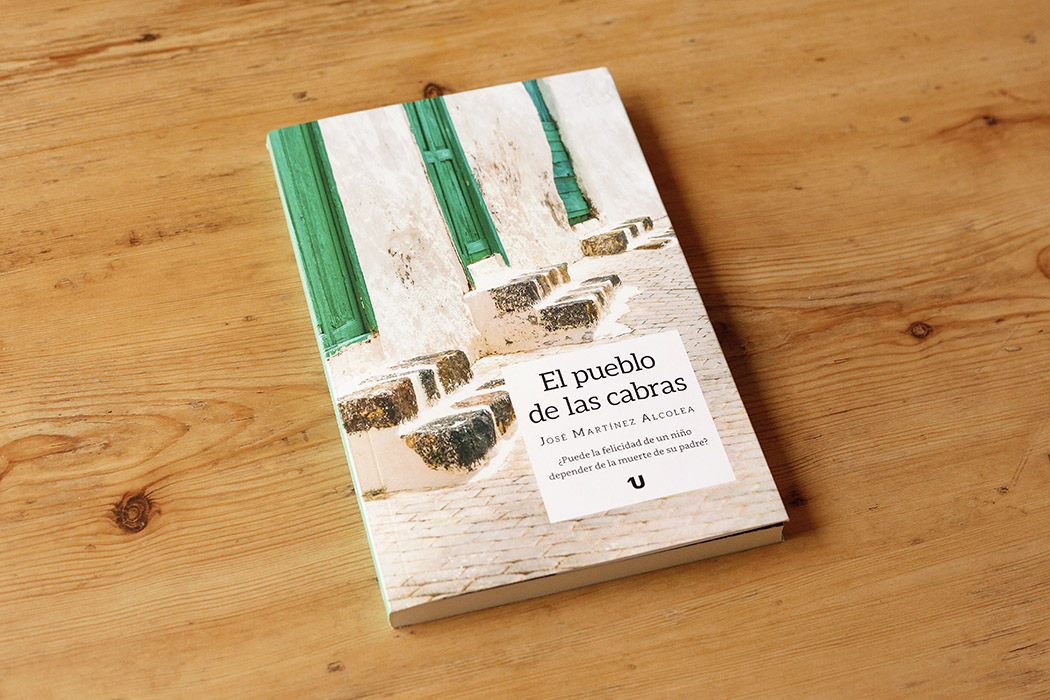 Foto del libro "El pueblo de las cabras" de José Martínez Alcolea, que muestra una calle de pueblo, encalada, con las puertas de las casas pintadas de un verde brillante.